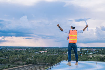 Rear view of man standing at observation point against sky