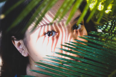 Close-up portrait of young woman by leaves