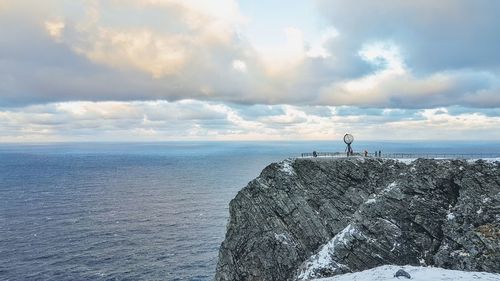 People standing on rock by sea against sky