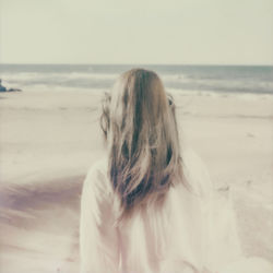 Rear view of woman on beach against sky
