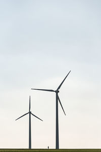 Two wind farms and a human silhouette showing the scale of windmill and man. 