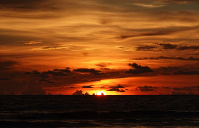 Scenic view of sea against dramatic sky during sunset