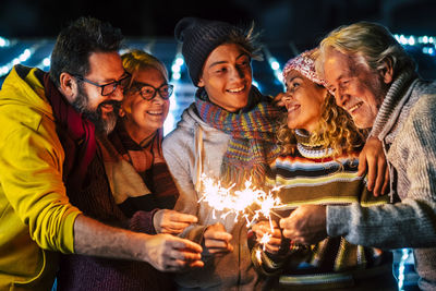 Smiling family holding sparkler outdoors at night