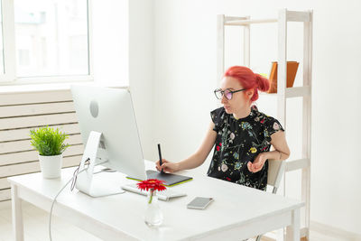 Young woman sitting on table at home