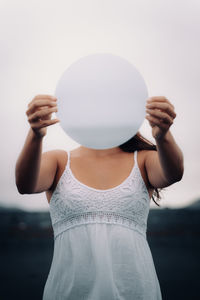 Midsection of woman holding umbrella while standing against white background