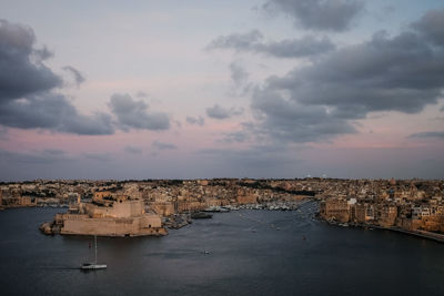 Aerial view of buildings and sea against sky at sunset