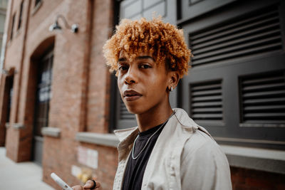 Portrait of young man standing against building