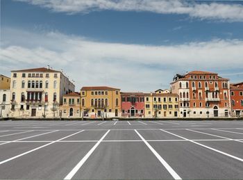 Empty road by buildings against sky