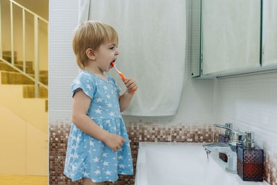 Little toddler girl brushes her teeth in the bathroom.