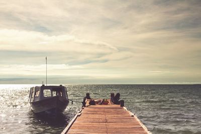 Pier on sea against cloudy sky