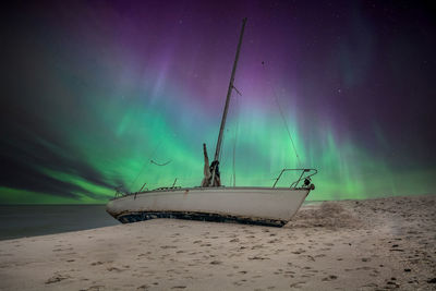 Aurora borealis over a shipwreck off the coast of uttakleiv beach in norway