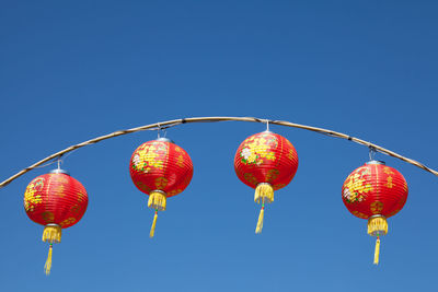 Low angle view of lanterns against clear blue sky during sunny day