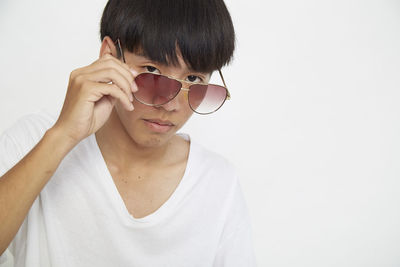 Portrait of man wearing sunglasses standing against white background