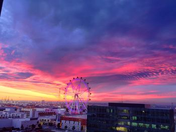 Cityscape against cloudy sky at sunset