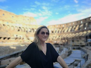 Portrait of smiling woman in sunglasses standing against sky