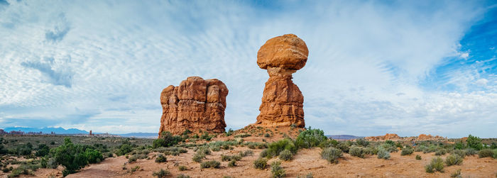 Rock formations on landscape against cloudy sky