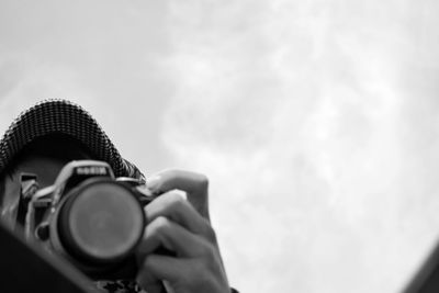 Low angle view of man photographing from camera against sky