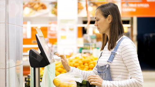 Woman weighing oranges at supermarket