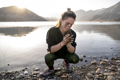 Woman putting mud on hands and face while enjoying outdoors in nature.