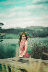 Beautiful young woman standing against sky