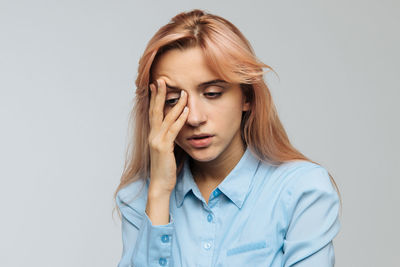 Young woman with head in hands against white background