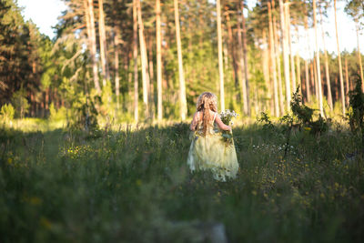 Rear view of girl walking on grassy field