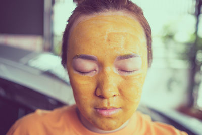 Close-up of young woman with facial mask at home