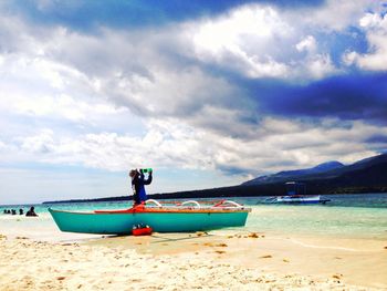 Boat moored on beach against sky