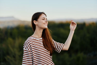 Portrait of smiling young woman standing against sky