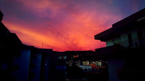 Silhouette houses against sky during sunset