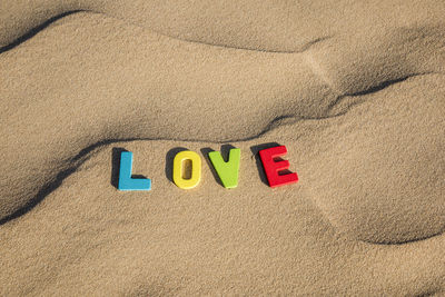 Love written out with colourful wooden letters text on sand of a dune