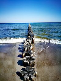 View of groyne on beach against clear sky