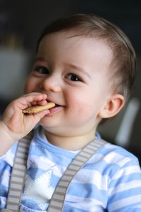 Close-up portrait of cute boy eating cookie