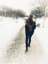 Full length of woman standing on snow covered field