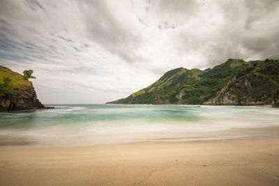 Scenic view of sea and mountains against cloudy sky