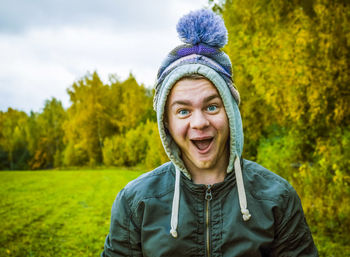 Portrait of happy young man with mouth open standing at park