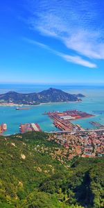 High angle view of townscape by sea against blue sky