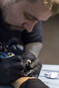 Close-up of artist making tattoo on leg