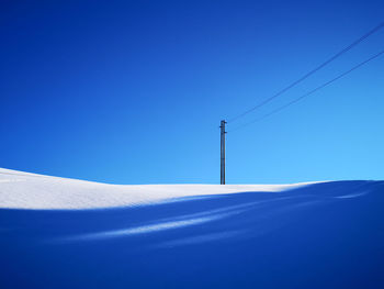 Low angle view of snowcapped mountain against clear blue sky