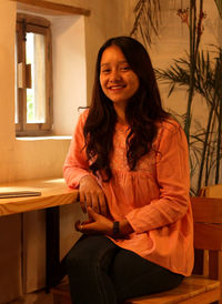 A girl smiling while sitting inside a cafe.