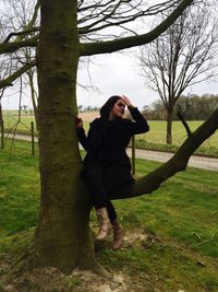 Woman standing by tree on field against sky