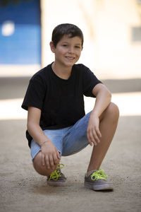 Portrait of boy crouching outdoors