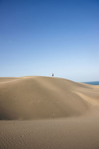 Scenic view of desert against clear blue sky