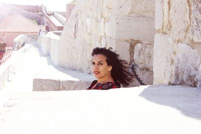 Portrait of woman against wall in sunny day