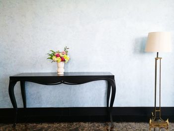 Flower vase on table against wall