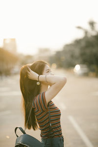 Side view of young woman with hands in hair