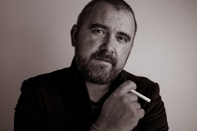 Portrait of man holding camera over gray background