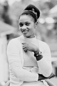 Portrait of smiling young woman with hair bun sitting outdoors