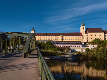 Buildings by river against blue sky