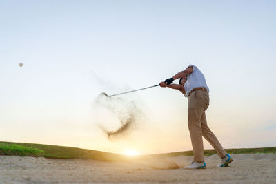 Low angle view of man playing golf against clear sky